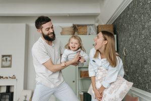 Happy parents dressed in white having fun with their child at home.