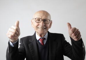 white background. elderly businessman smiles and gives two thumbs up