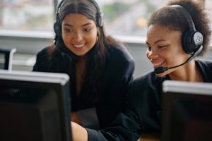 two business women smile as they work on the computer