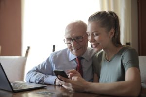 smiling insurance agent helping elderly business owner apply for Prudential Life Insurance on his mobile phone