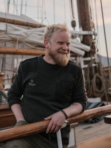 smiling boat captain leaning over his ship